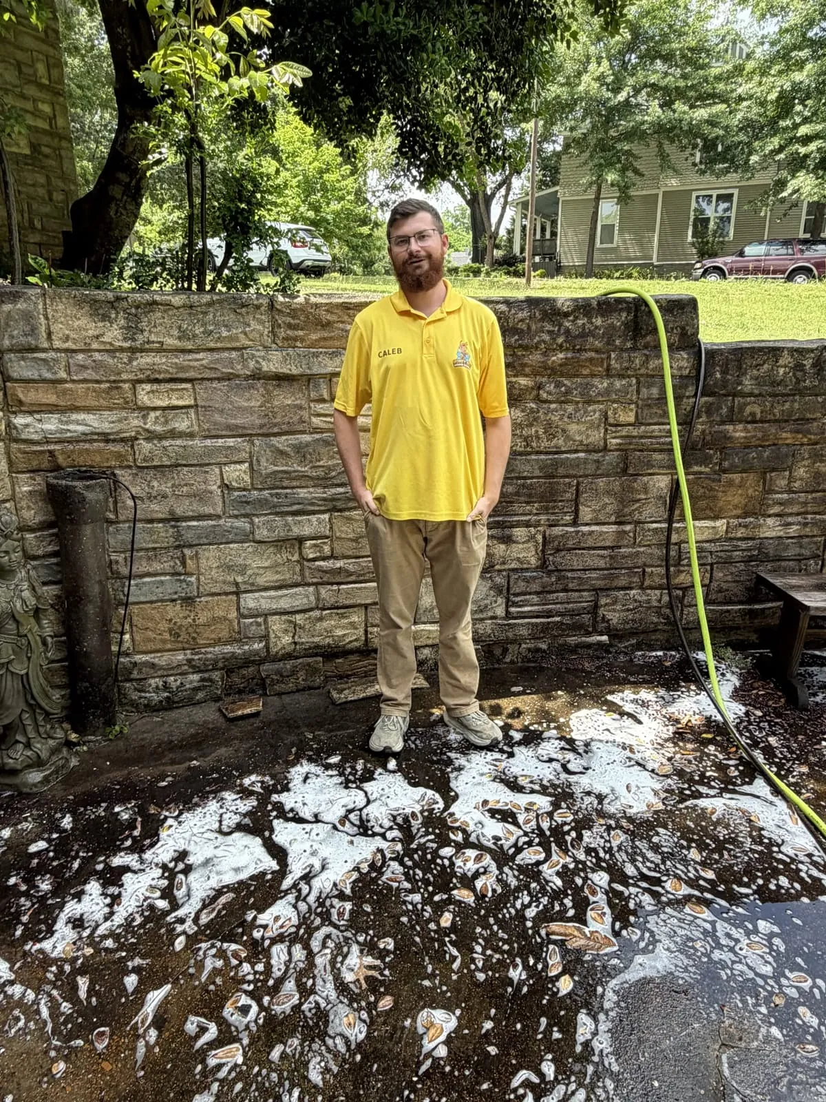 Caleb Honey, owner of HoneyBee Window Cleaning, on a freshly soft-washed patio