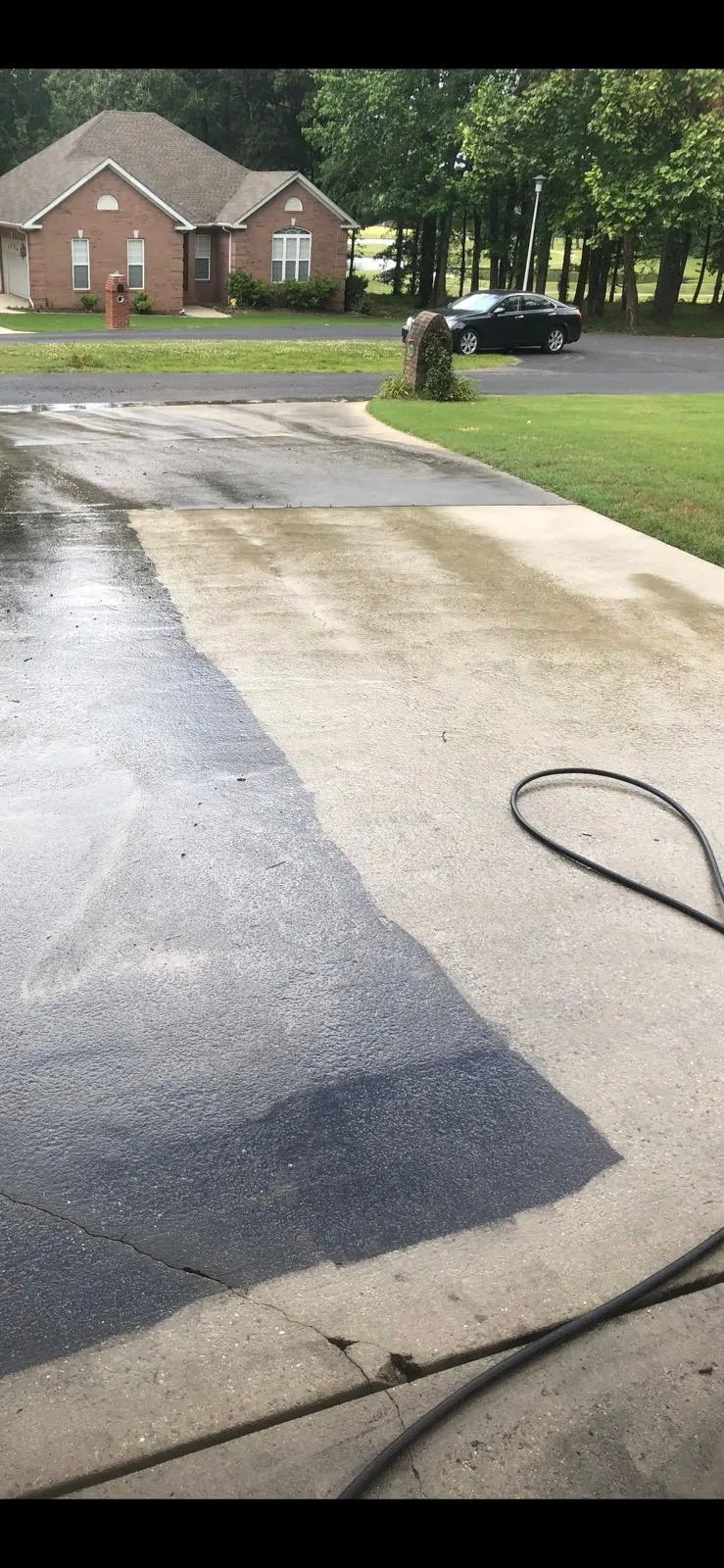 Concrete driveway half pressure washed, showing a sharp clean line