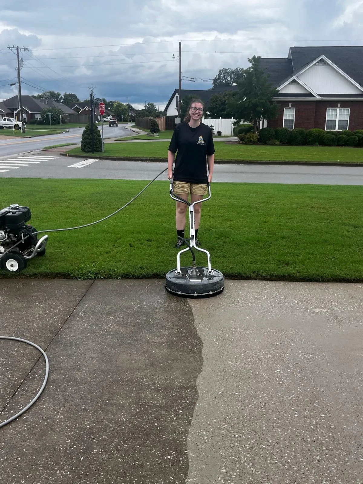 HoneyBee crew member running a surface cleaner across a concrete driveway