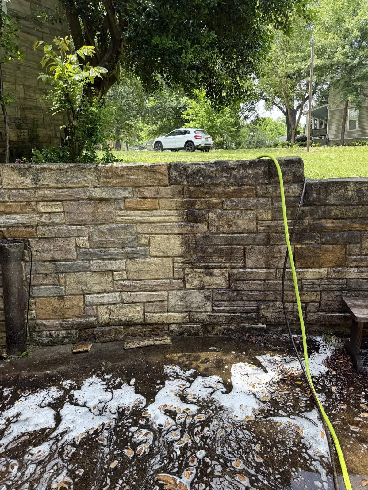 Stone wall dark with algae and grime before soft washing